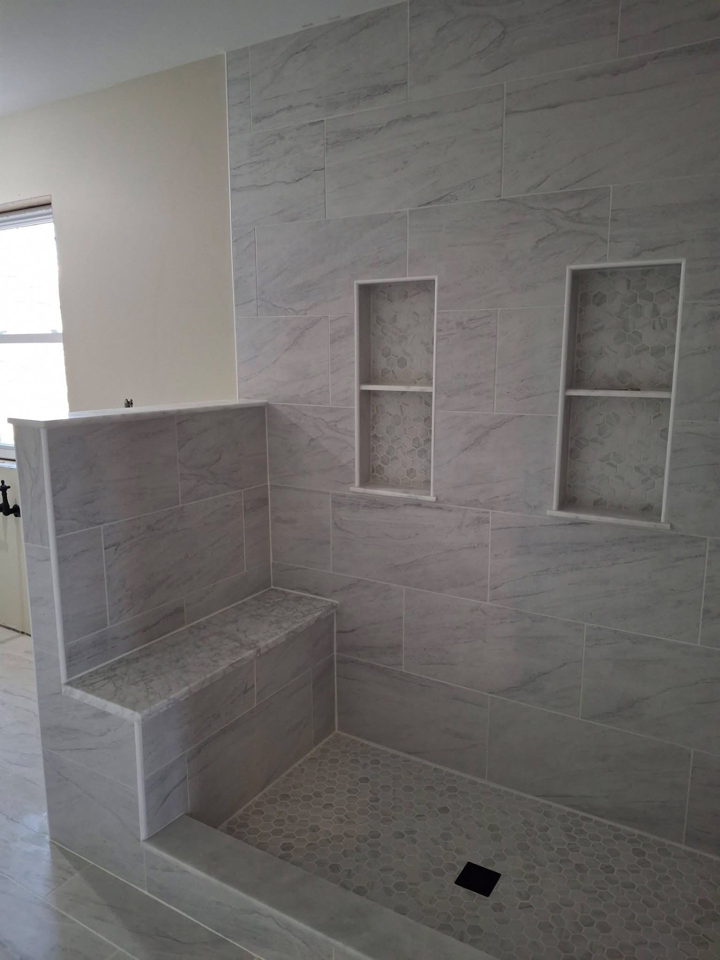 Marble tile shower with custom bench